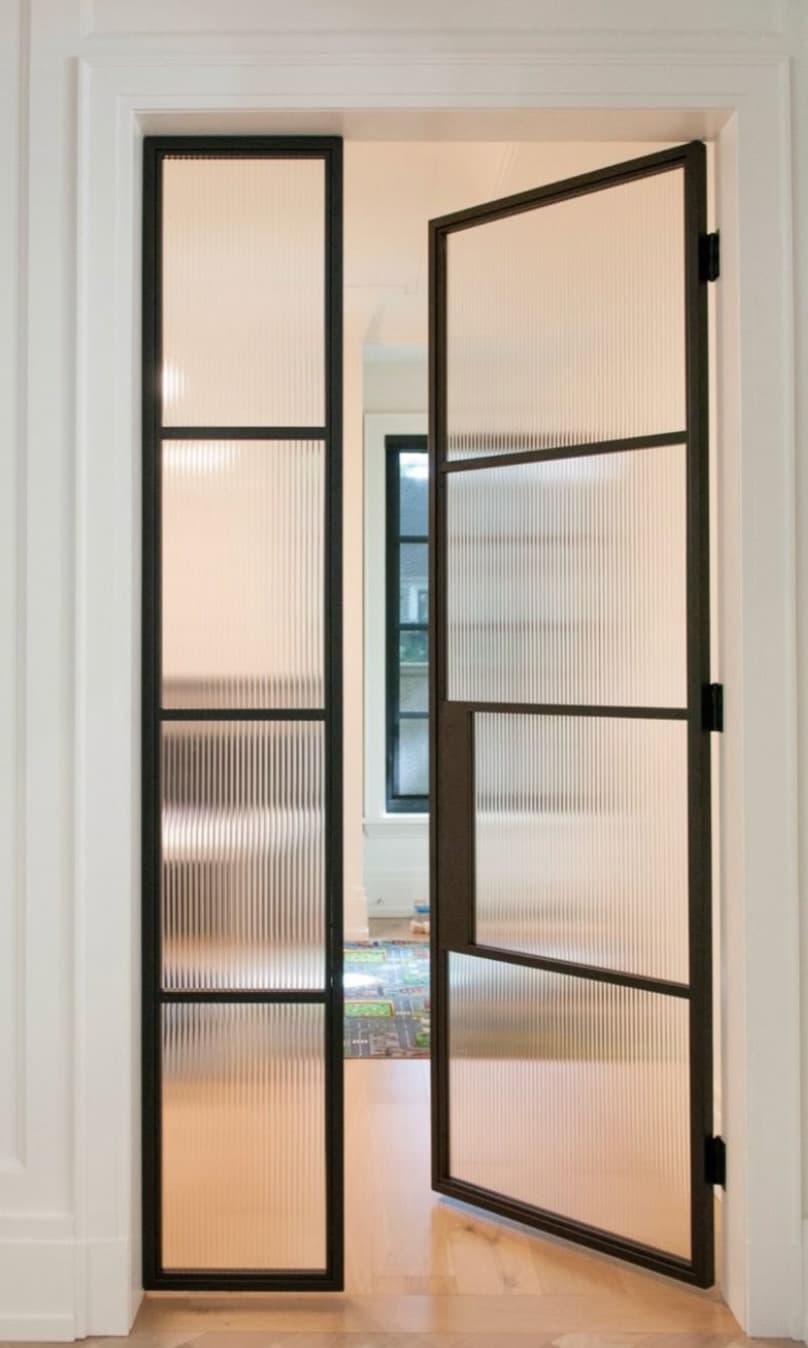 Black steel French-style doors with fluted glass, installed in a residential interior