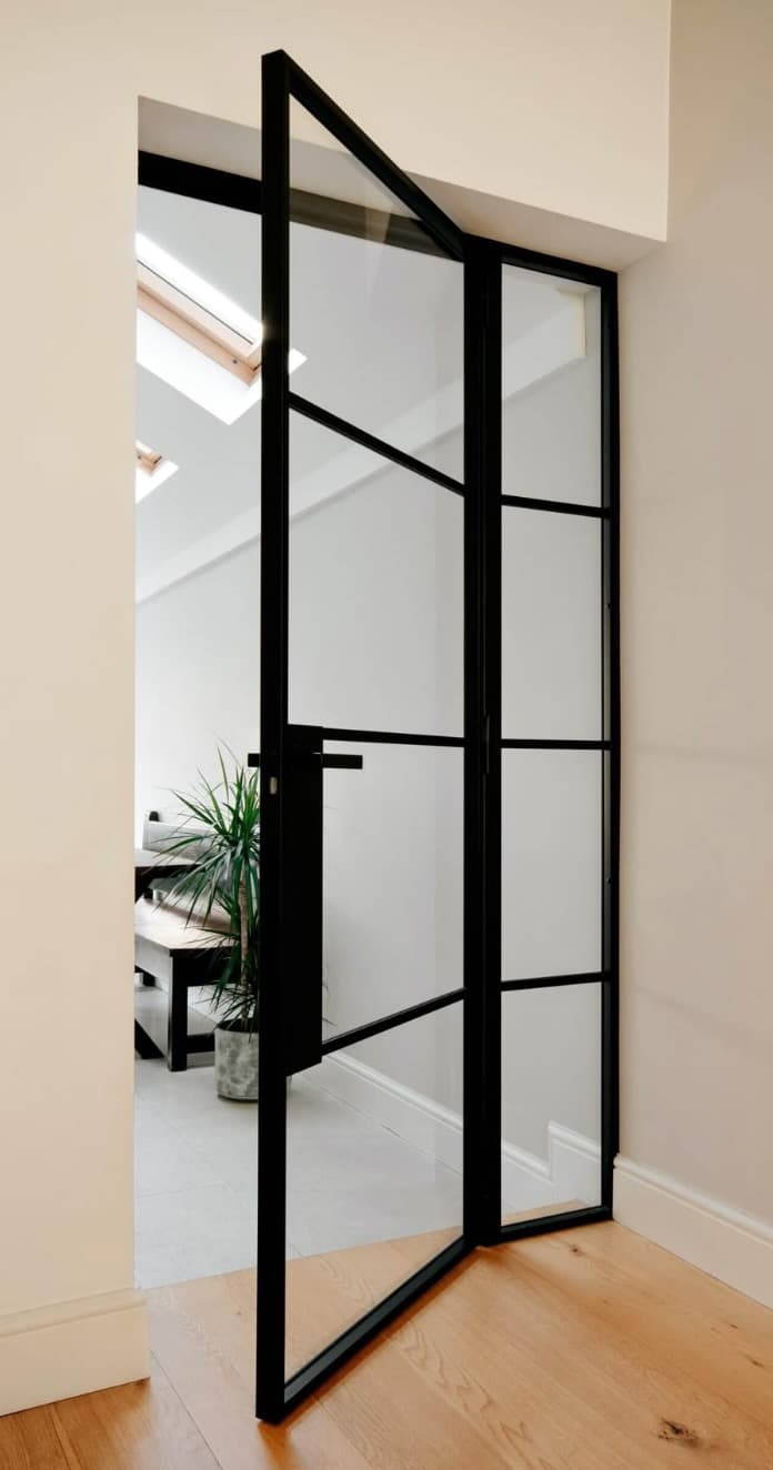 Slim black steel French-style door, slightly ajar, in a bright residential interior