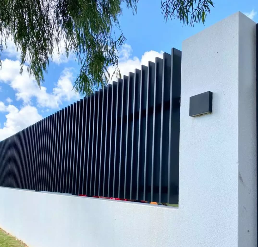Vertical black steel screen fins on a white rendered boundary wall